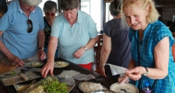 Die Touristen nehmen an einem Kochkurs auf LaFairy Sails Dschunke teil