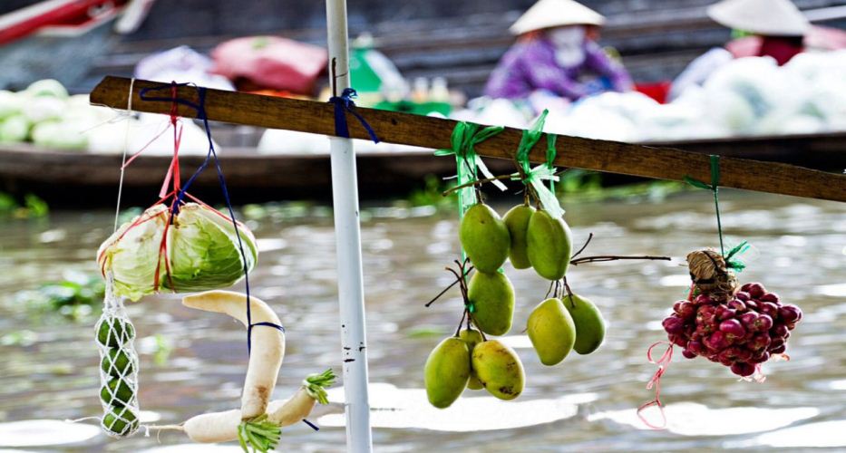 Aufgehängte Kaufwaren am Bug eines Bootes auf dem Markt Cai Be